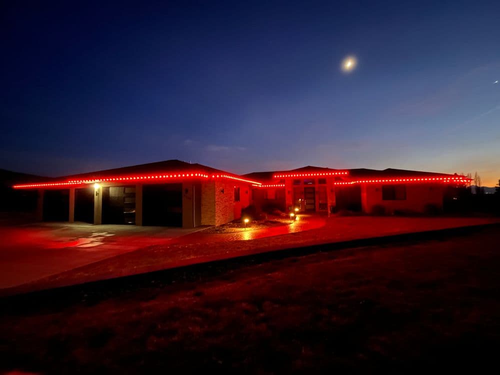 House illuminated with red lights at night against a twilight sky.